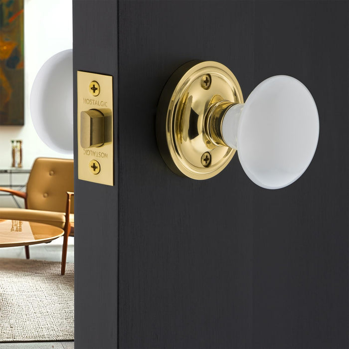 Nostalgic Warehouse 702208 Classic Rosette With White Porcelain Door Knob Passage 2.375in Polished Brass