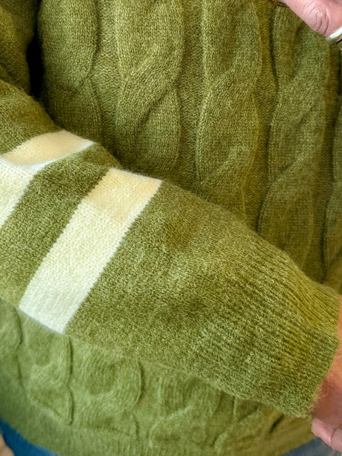 Olive cable knit sweater sleeve with cream-white stripe cuff and ribbed hem