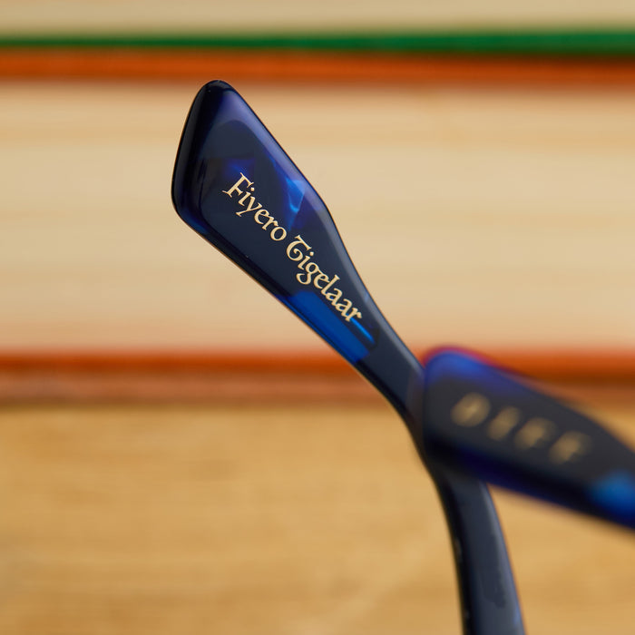 lifestyle - wicked x diff eyewear featuring the prince fiyero square sunglasses with a regal blue tortoise frame and brown gradient lenses detailed view of temple tip with Fiyero Tigelaar's name