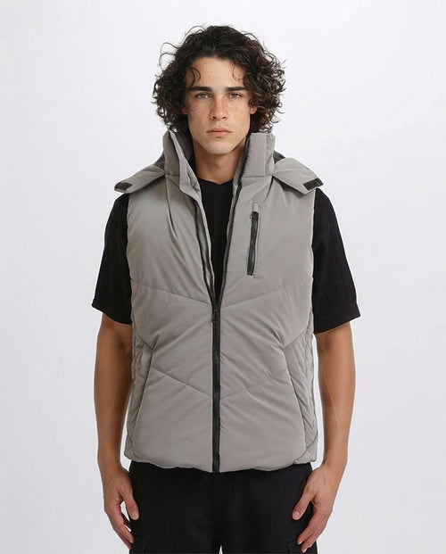 Man wearing a gray vest over a black shirt on a white background