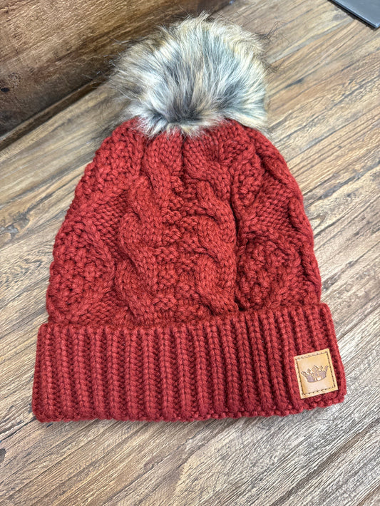 Red cable-knit pom beanie with ribbed brim, gray faux-fur pom, leather logo tag