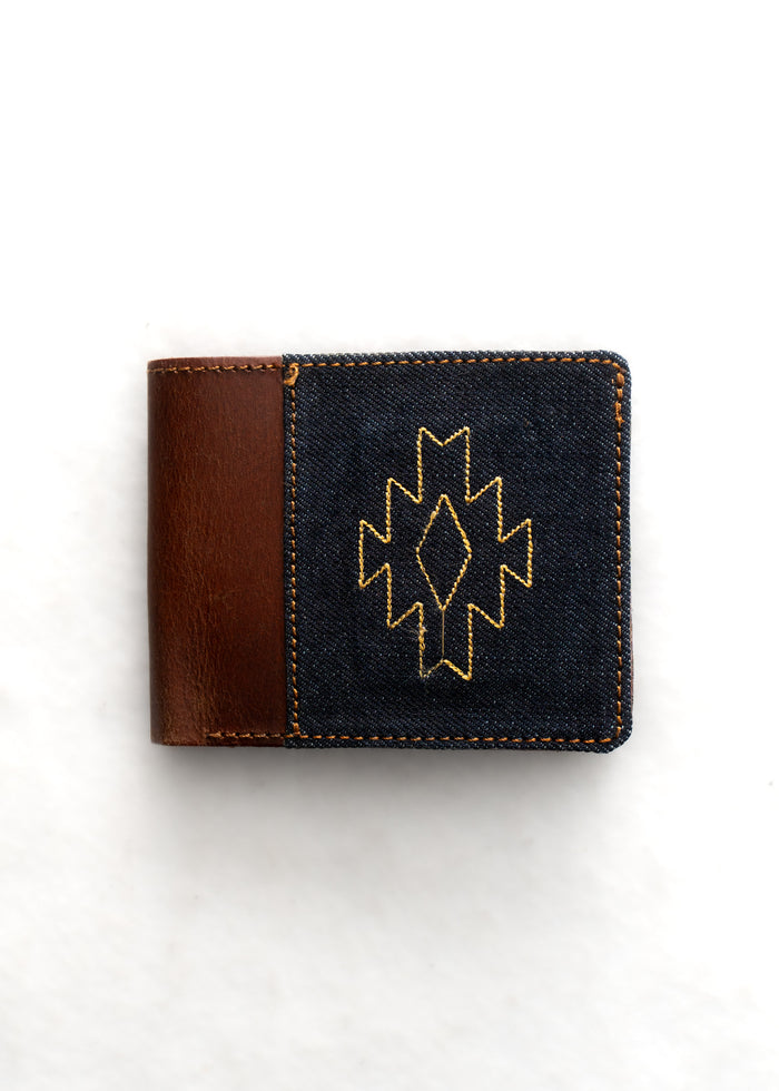 Brown leather wallet with a denim front, featuring a yellow geometric pattern. Simple and stylish design on a white background.