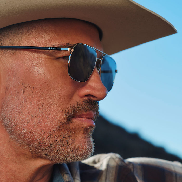 lifestyle - male riding a horse wearing yellowstone x diff eyewear featuring the rip wheeler navigator sunglasses with a silver frame and grey polarized lenses side view