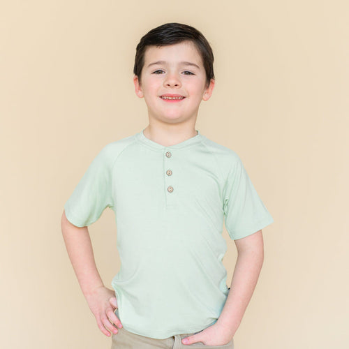 Young boy modeling the Short Sleeve Toddler Henley Tee in Basil