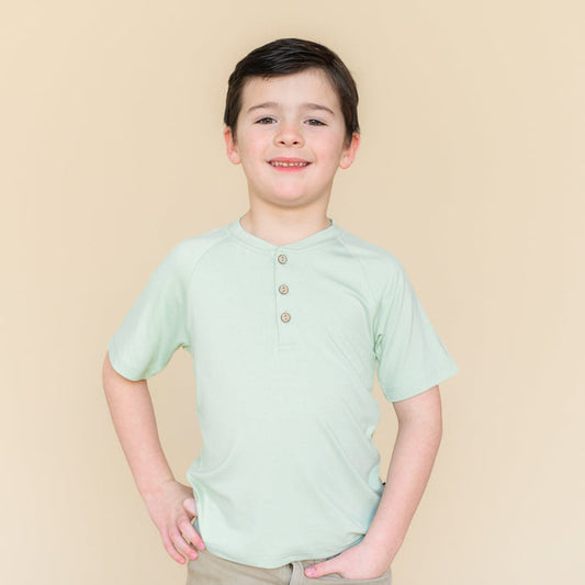 Young boy modeling the Short Sleeve Toddler Henley Tee in Basil