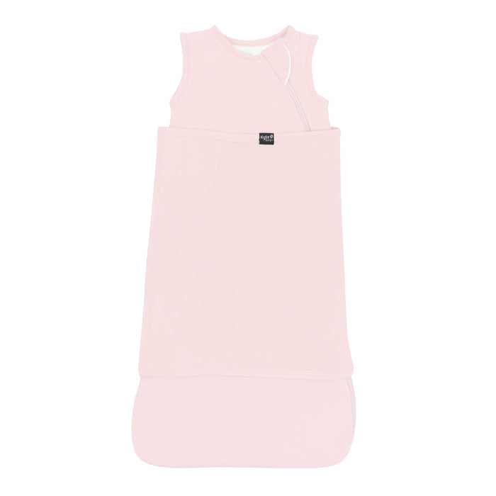 Sleep Bag Swaddler in Blush 1.0 shown swaddled with the Black Kyte Baby logo visible
