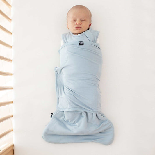 Newborn sleeping in a crib swaddled in the Sleep Bag Swaddler in Fog 1.0