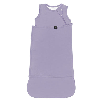 Sleep Bag Swaddler in Taro 1.0 shown swaddled with the black Kyte Baby logo tag visible