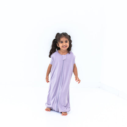 Smiling model wearing the Sleep Bag Walker in Taro 0.5