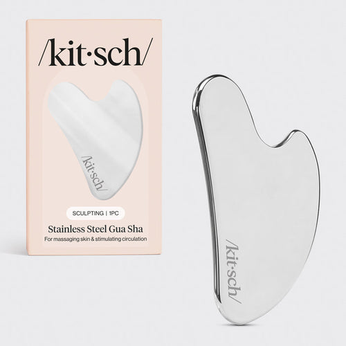 Kitsch Stainless Steel Gua Sha tool lying flat on marble surface showing curved edges