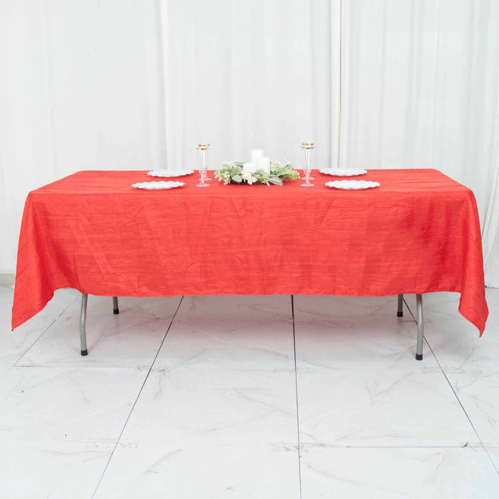 Red tablecloth on a dining table with plates and decorations.