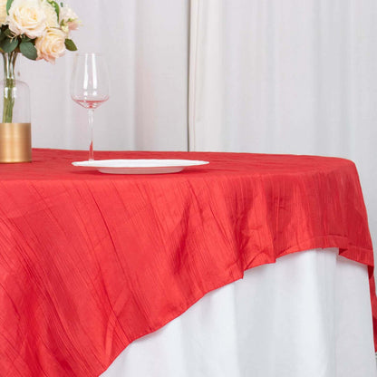 Red tablecloth draping over a white table with a wine glass and plate.