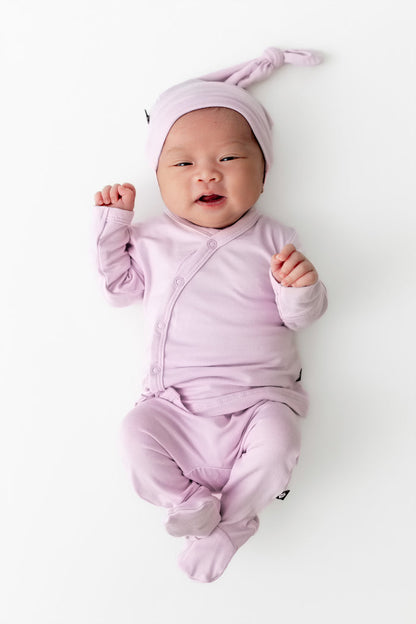 Baby wearing a light purple outfit and hat on a white background