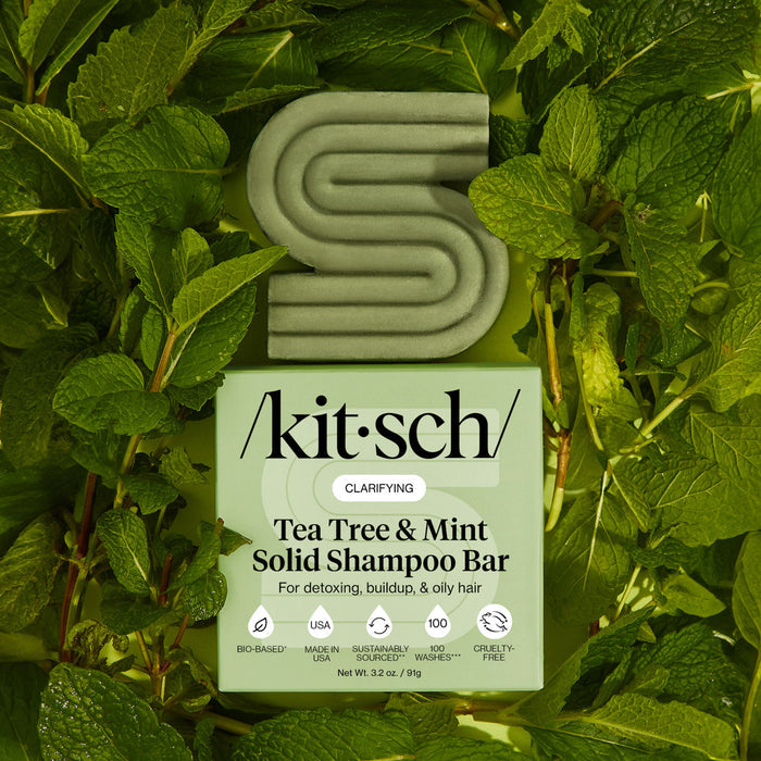 KITSCH Tea Tree & Mint Clarifying Solid Shampoo Bar and packaging box displayed on lush fresh mint leaf background — labeled CLARIFYING, For oiliness, buildup, & oily hair — bottle-free clarifying shampoo bar for oily, buildup-prone hair and scalp
