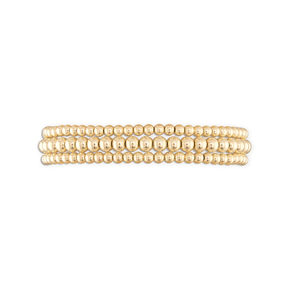A stack of three gold-colored ball bracelets with an elastic stretch band.
