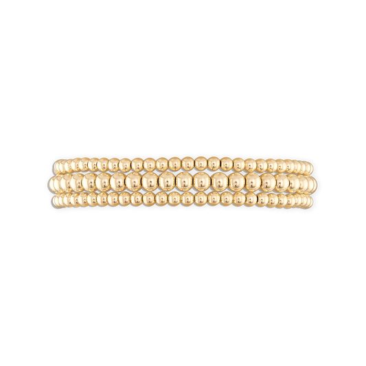 A stack of three gold-colored ball bracelets with an elastic stretch band.