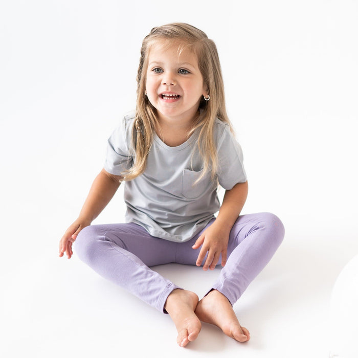 Girl sitting in a white room wearing Leggings in Toddler and a Tee in Storm
