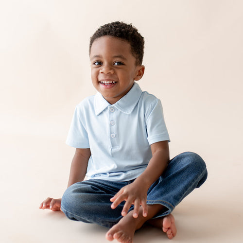 Young boy wearing a light blue polo short sleeve top and jeans