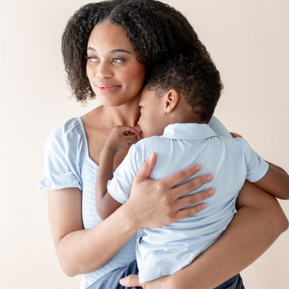Woman holding a child against a plain background