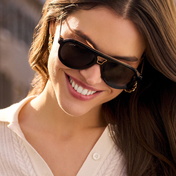 on model - female wearing diff eyewear featuring the tosca iii aviator sunglasses with a black frame with gold rim and grey polarized lenses angled view