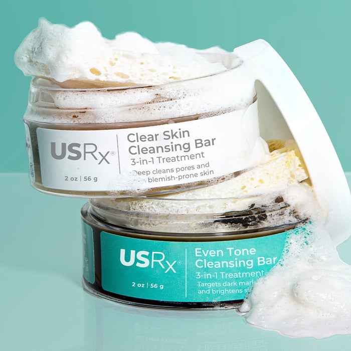 Two open jars of USRx Cleansing Bars with suds coming out of the jars against a light blue background