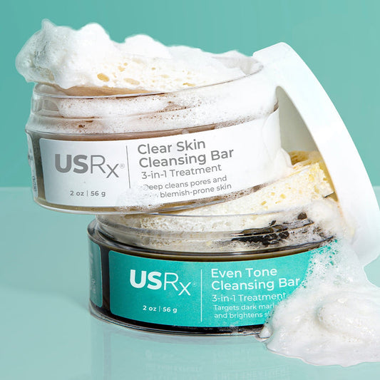 Two open jars of USRx Cleansing Bars with suds coming out of the jars against a light blue background