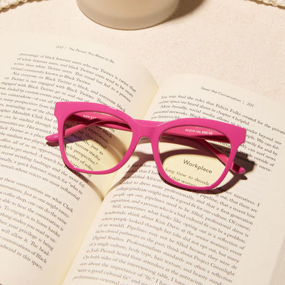 still life of the diff eyewear willa square prescription glasses with a bubble gum pink acetate frame laying on a open book