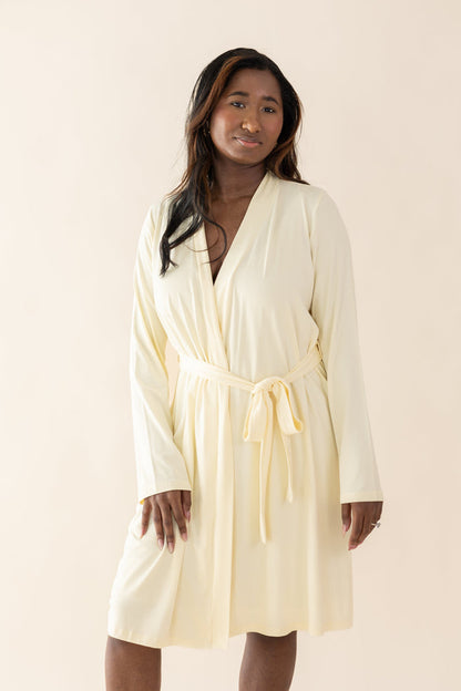 Woman wearing a yellow-colored robe against a plain background