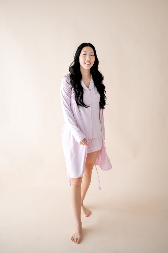 Woman wearing a light purple robe with matching PJ set against a plain background