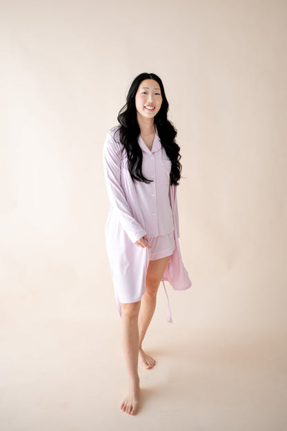 Woman wearing a light purple robe with matching PJ set against a plain background