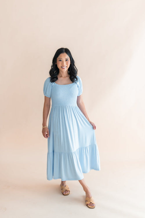 Female modeling the Women’s Smocked Dress in Breeze standing in front of a light neutral background