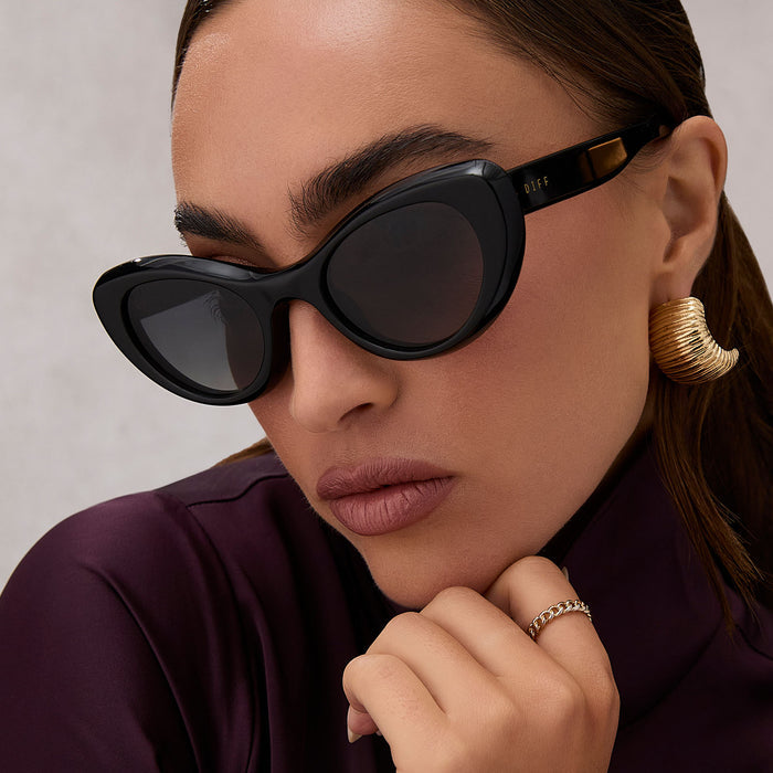 on model - female wearing diff eyewear featuring the zaria cat eye sunglasses with a black frame and grey gradient lenses angled view