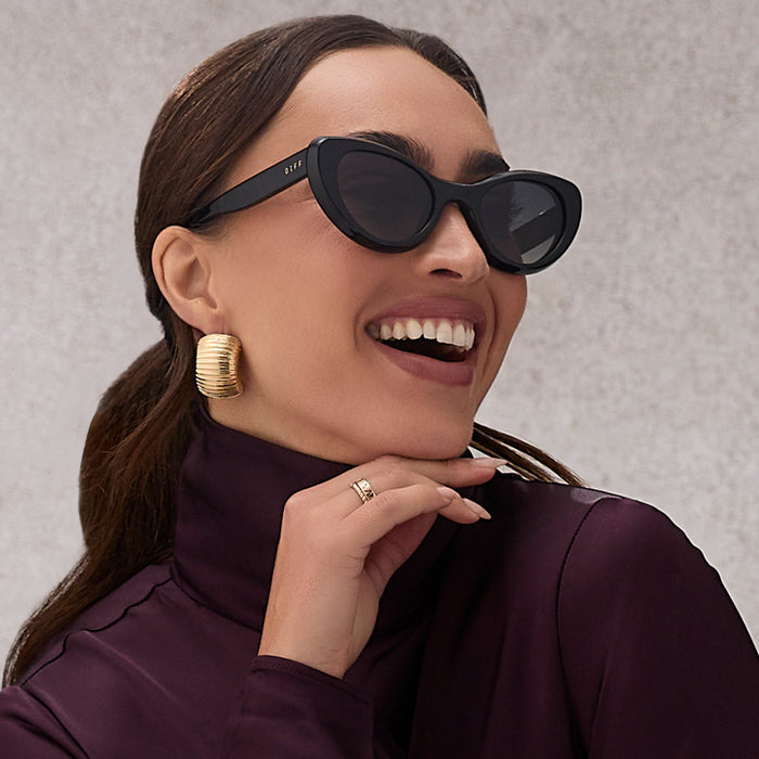 on model - female wearing diff eyewear featuring the zaria cat eye sunglasses with a black frame and grey gradient lenses angled view